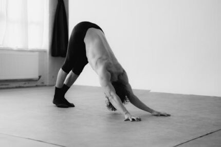 Black and white photo of a man in a yoga backbend pose indoors, Berlin studio.